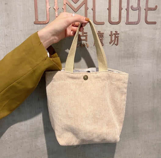 Beige tote bag held by a hand