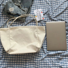 Beige tote bag, denim jacket, and beige laptop on a checkered fabric background