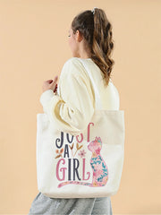 Person holding a tote bag with 'Just a Girl' design on a beige background