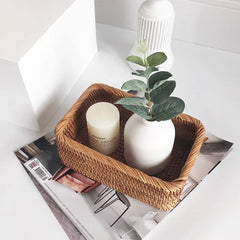 Wicker Handwoven Rattan Storage Basket with a candle and small plant on a magazine