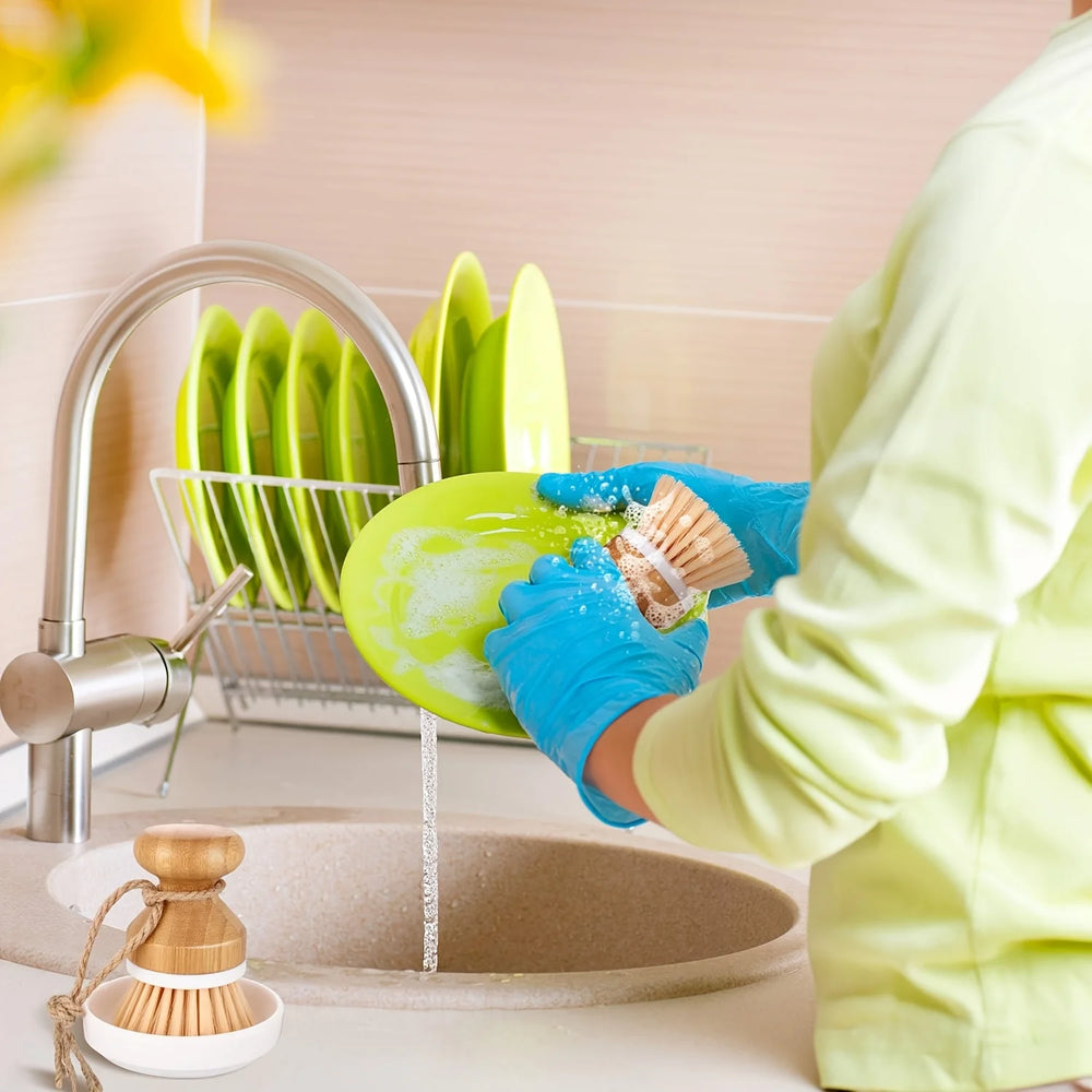 Person washing green dishes in a kitchen sink with a dish rack
