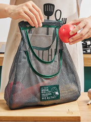 Person placing a tomato into a Reusable Mesh Storage Bag