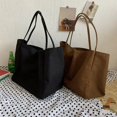 Black and brown tote bags on a polka dot surface with a white wall background.
