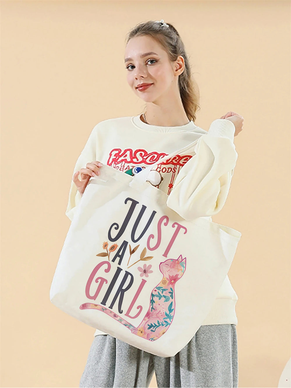 Woman holding a tote bag with 'Just a Girl' design on a beige background