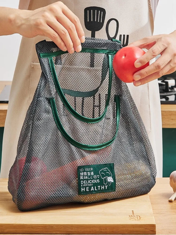 Person placing a tomato into a Reusable Mesh Storage Bag